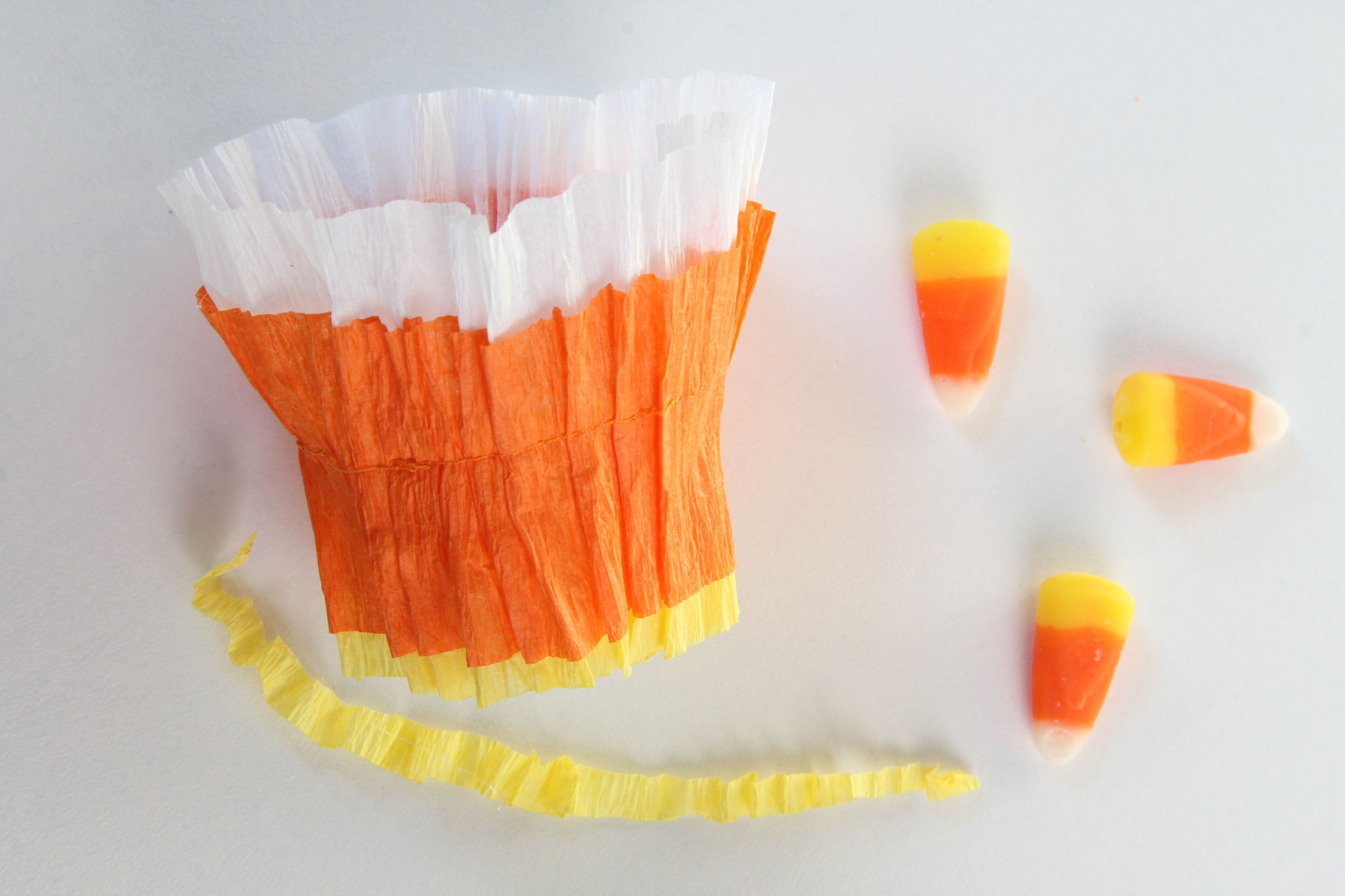 Cut any overhanging paper from the assembled DIY candy Corn Baskets. That way they can stand flat on a table.